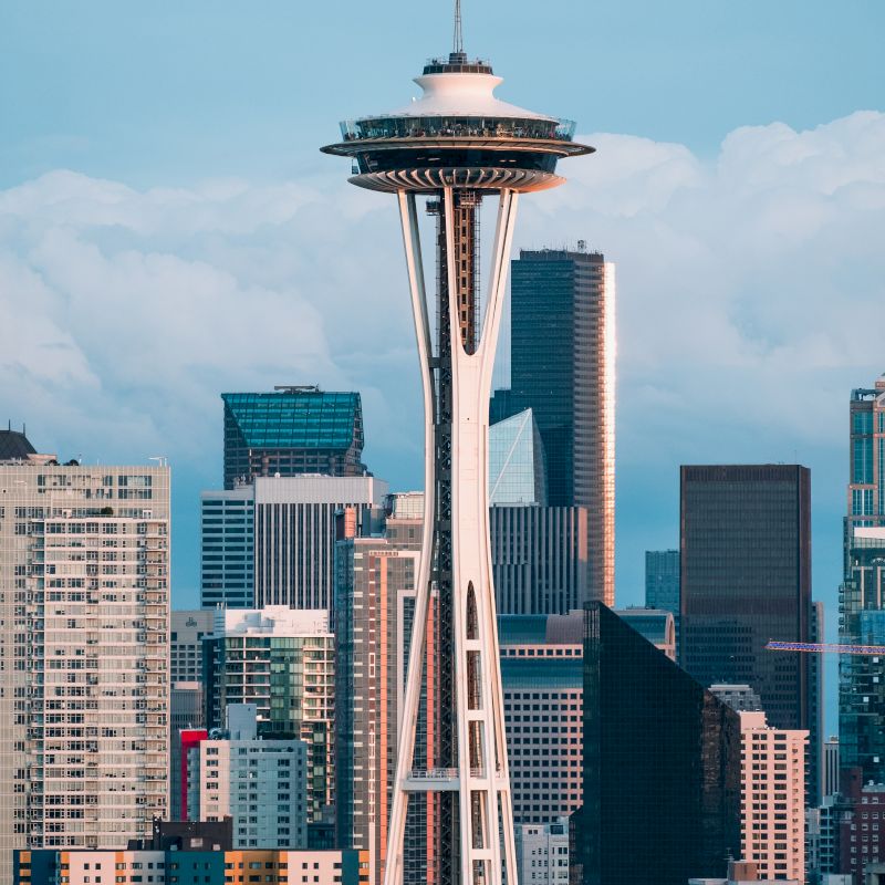 The image shows the Space Needle, an iconic observation tower in Seattle, with the city's skyline and various high-rise buildings in the background.