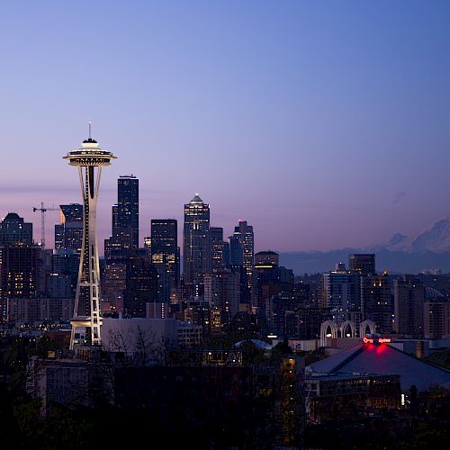 This image shows the Seattle skyline at dusk with the Space Needle prominently featured and Mount Rainier visible in the distance.