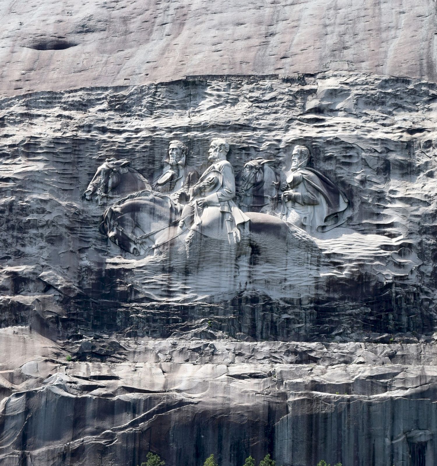 The image shows a large rock carving depicting three men on horseback, chiseled into the side of a mountain.